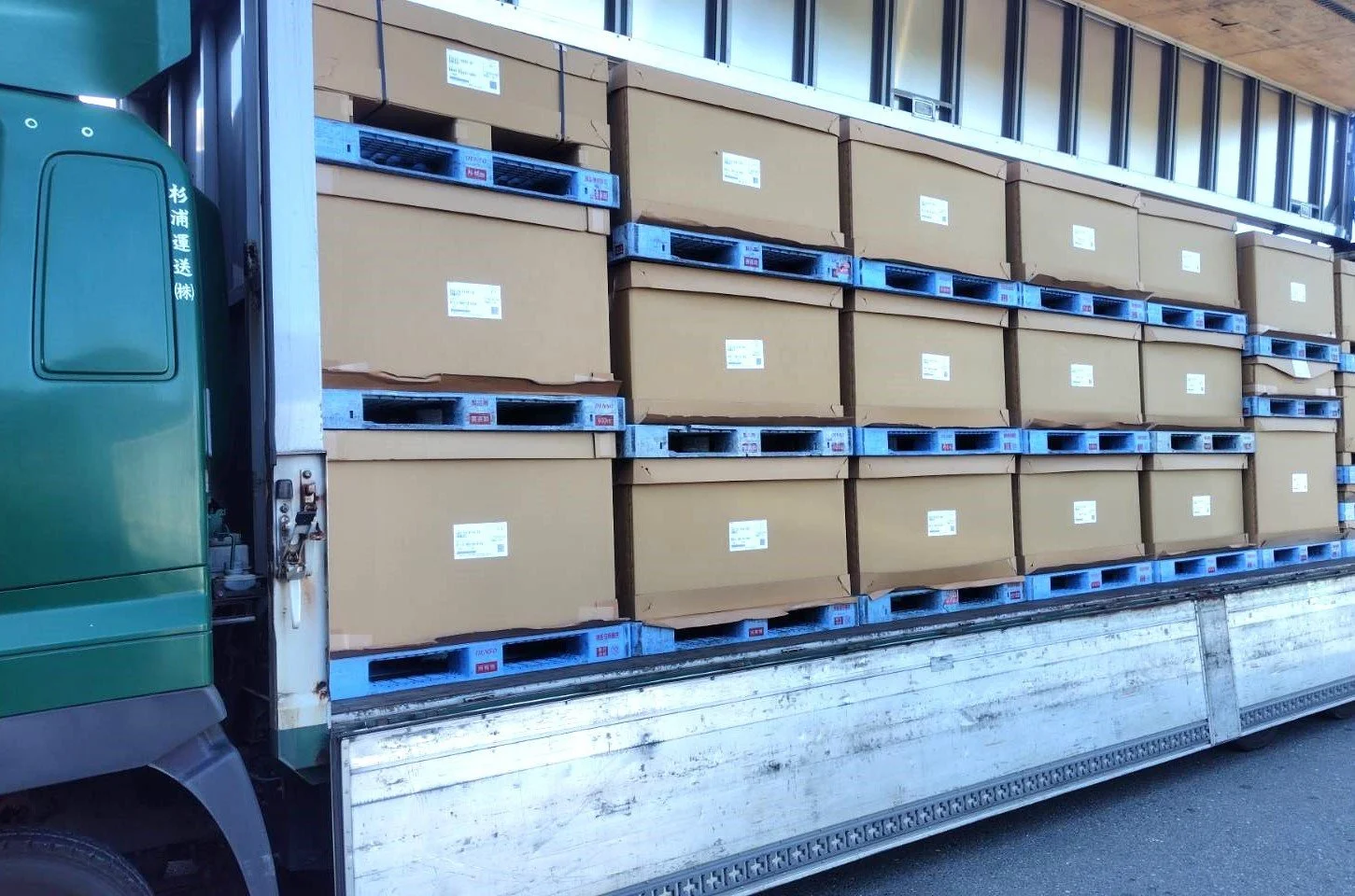 倉庫前で配送車両に出荷荷物を積み込む物流スタッフ